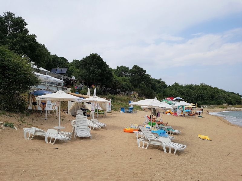 Het strand met witte strandstoelen en parasols bij camping Laguna Village