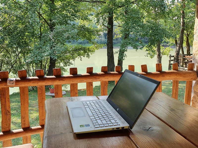 Laptop op houten tafel met uitzicht op rivier