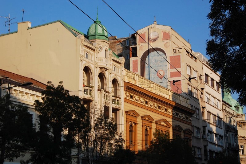 Mooie gebouwen in Belgrado, met muurschildering van luchtballon op kopse kant van één ervan.