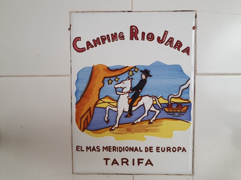 Tegeltje met tekst 'camping Rio Jara' en afbeelding van ruiter te paard, rivier met boot en bergen