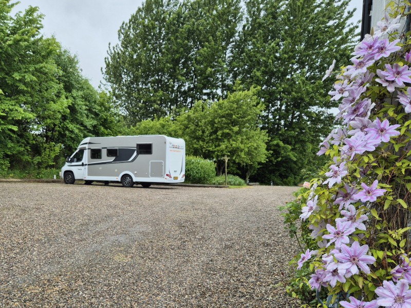 Campertrip naar Noorwegen- Onze camper en op de voorgrond bloeiende clematis