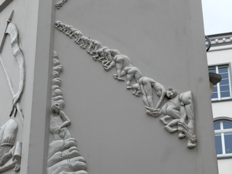 Detail van de zuil met enorme ijrij mensfiguren die hun bloten billen laten zien