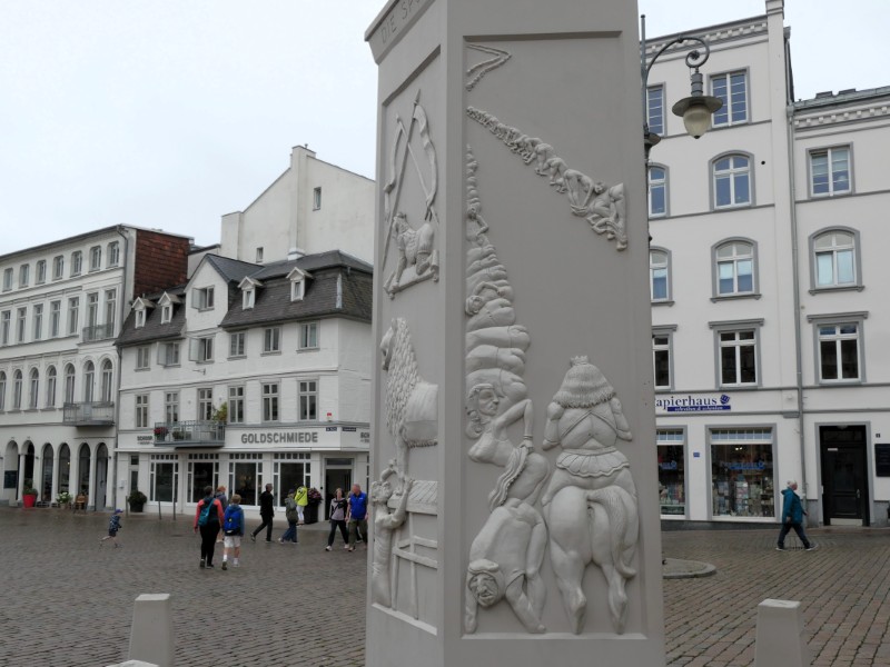 Relief op de zuil met mensfiguren die hun blote billen laten zien